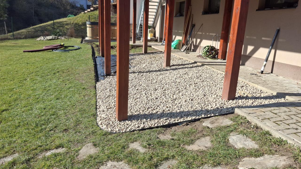Hotový pruh praného kačírku pod dřevěnou terasou – po