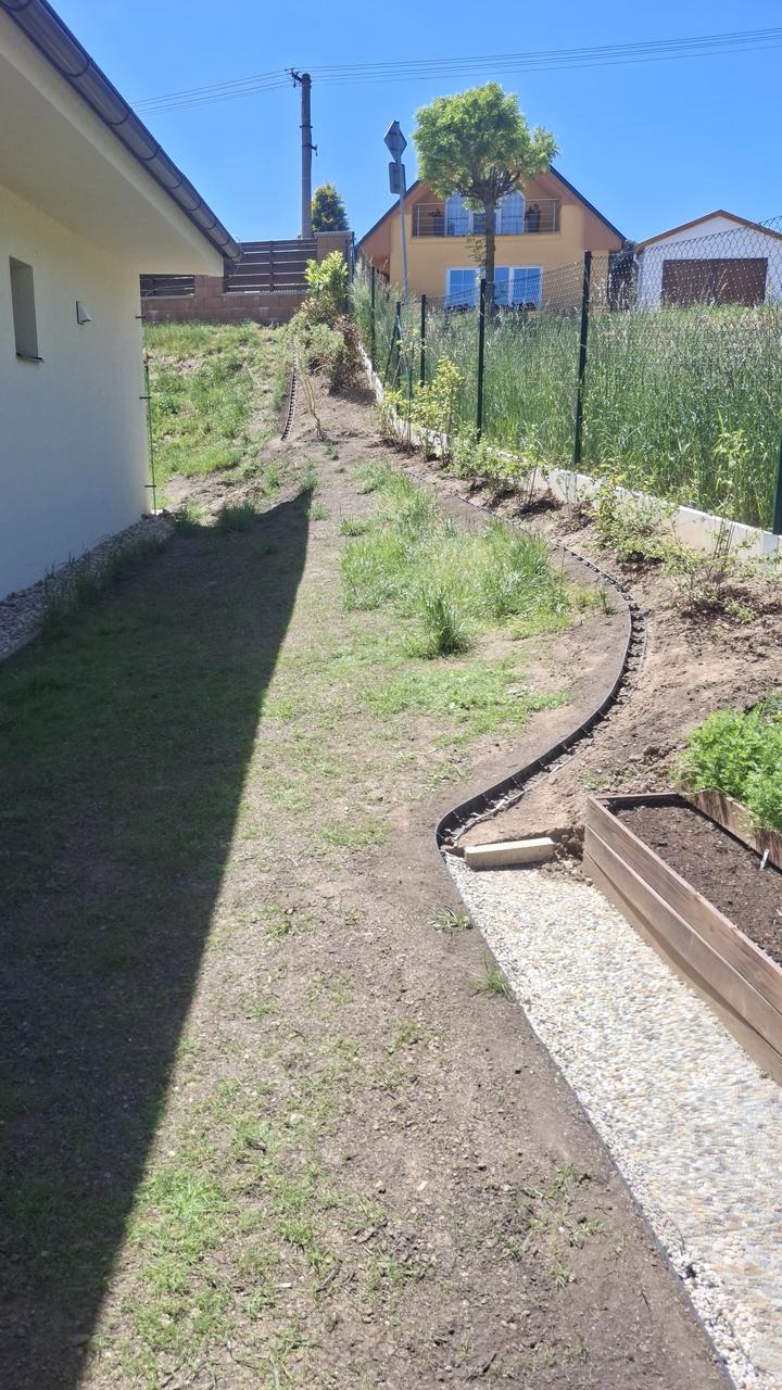 Zatravněný svah s kačírkovou cestičkou k záhonům – po